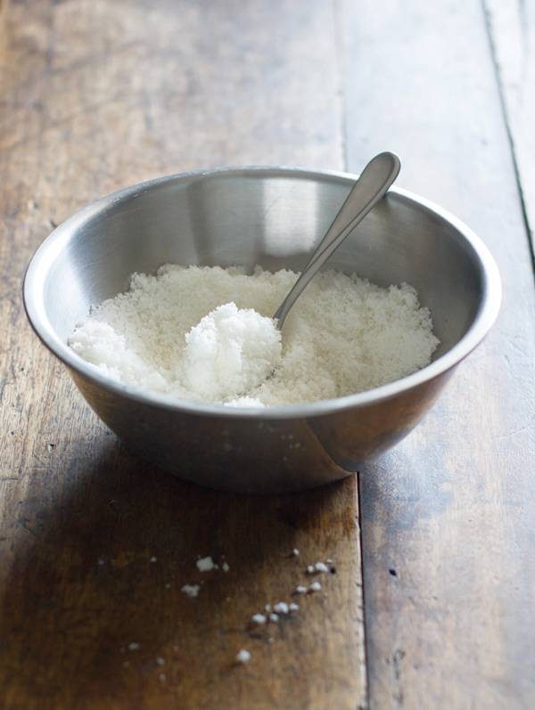 Coconut flakes in a mixing bowl with a spoon.